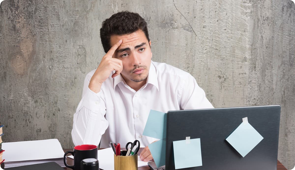 Frustrated man at his desk, staring past his laptop